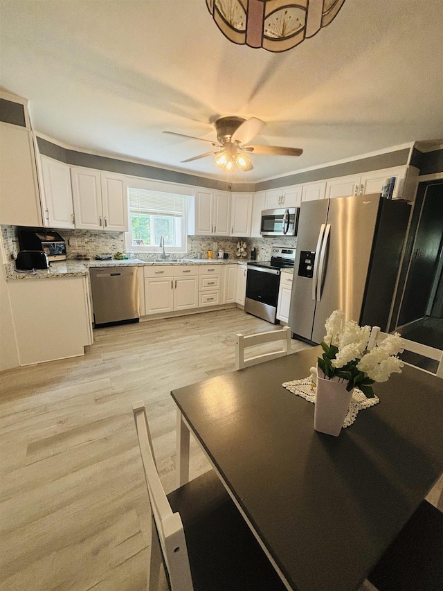 kitchen with ceiling fan, stainless steel appliances, tasteful backsplash, white cabinets, and light wood-type flooring