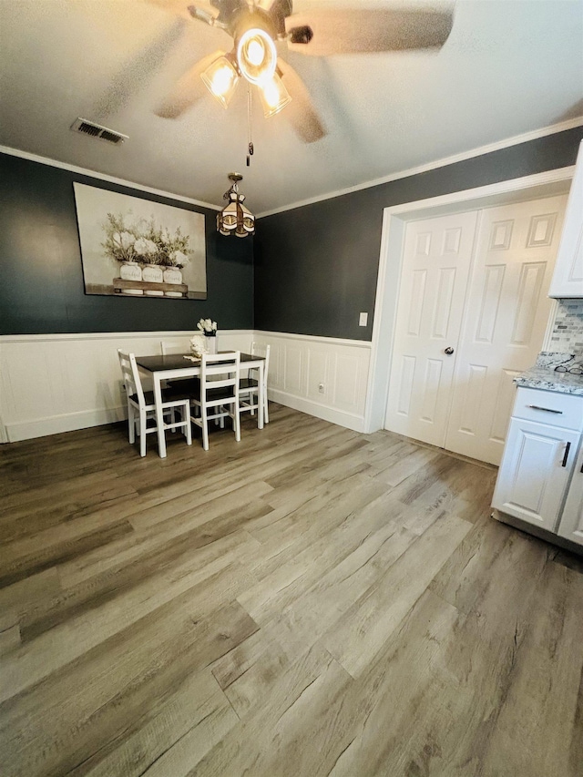 dining area featuring hardwood / wood-style floors, crown molding, and ceiling fan