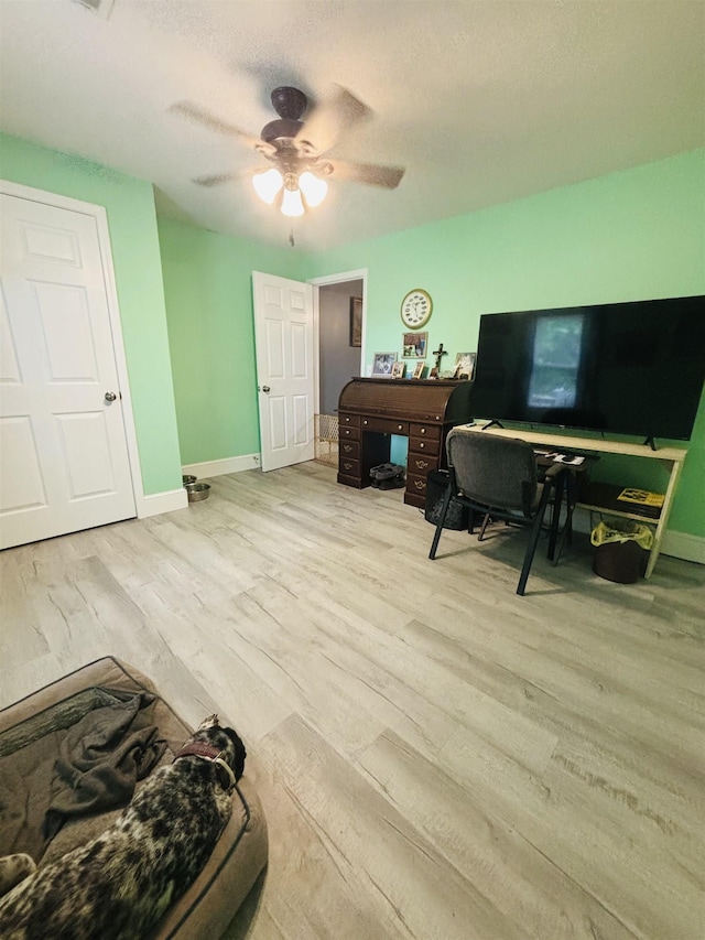 interior space with ceiling fan, a textured ceiling, and light hardwood / wood-style floors