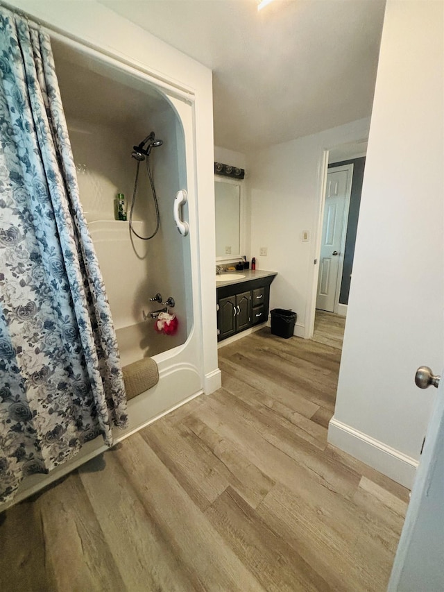 bathroom with wood-type flooring, vanity, and shower / bath combo with shower curtain