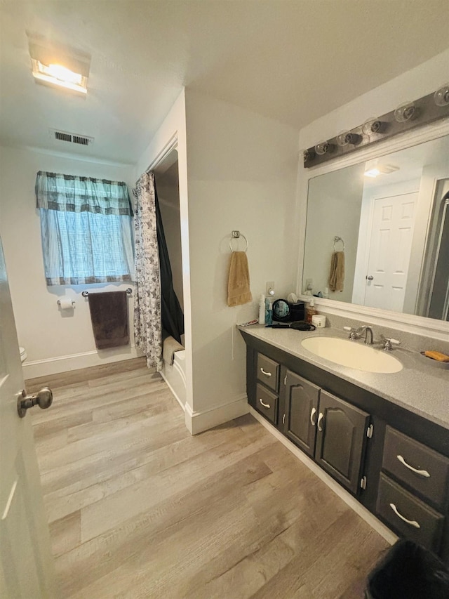 bathroom with wood-type flooring, shower / tub combo, and vanity