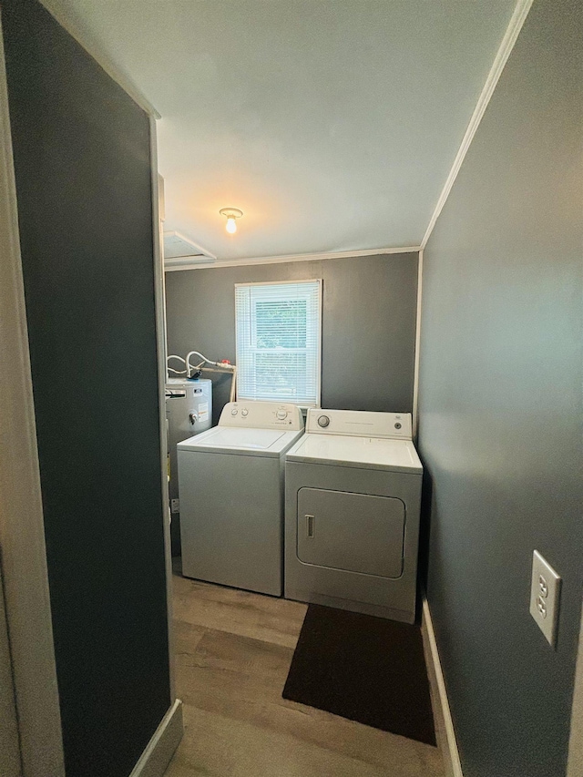 clothes washing area with crown molding, washer and clothes dryer, and light hardwood / wood-style flooring