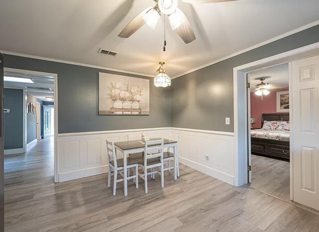 dining space with ornamental molding, ceiling fan, and light wood-type flooring