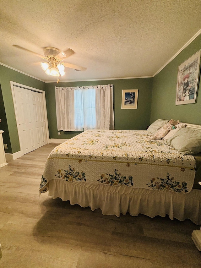 bedroom featuring ceiling fan, ornamental molding, light hardwood / wood-style flooring, and a textured ceiling