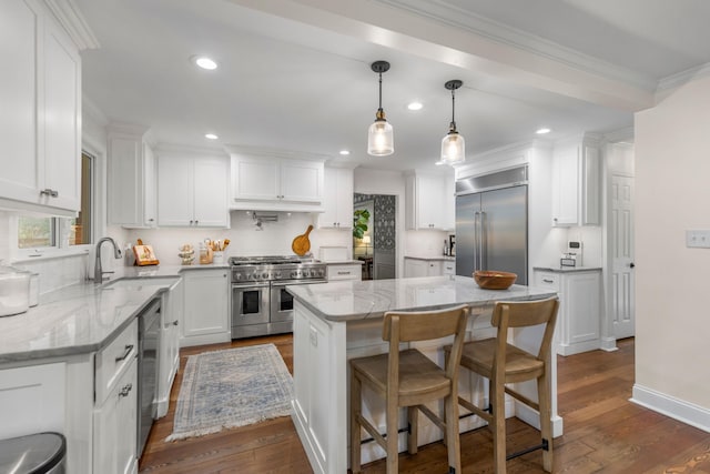 kitchen featuring sink, white cabinetry, light stone counters, high quality appliances, and a kitchen island