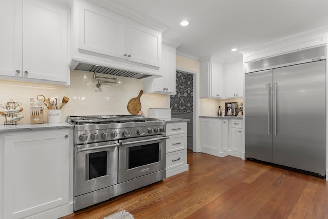 kitchen featuring high end appliances, dark hardwood / wood-style flooring, white cabinets, and premium range hood