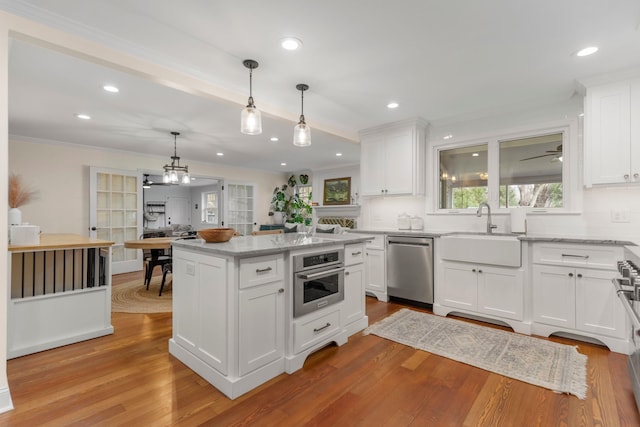 kitchen featuring white cabinetry, sink, decorative light fixtures, and stainless steel appliances