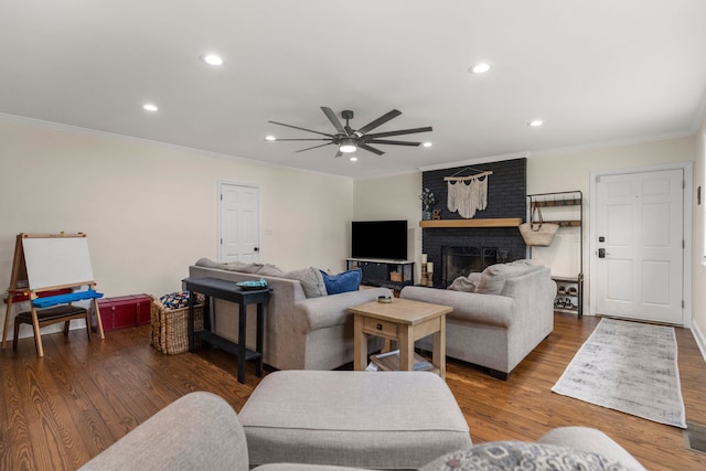 living room with ceiling fan, ornamental molding, dark hardwood / wood-style floors, and a fireplace