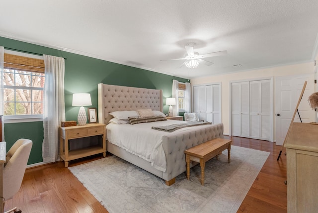 bedroom with ceiling fan, a textured ceiling, light hardwood / wood-style flooring, and multiple closets