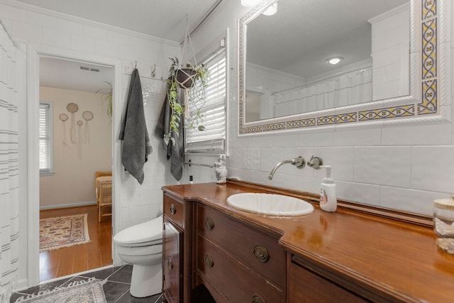 bathroom featuring tile walls, vanity, ornamental molding, and toilet