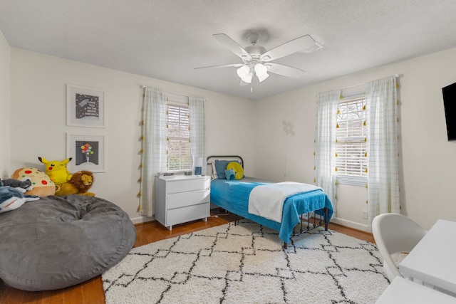 bedroom with ceiling fan, a textured ceiling, and light hardwood / wood-style floors