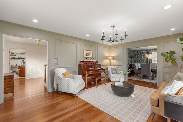 living room featuring ornamental molding, wood-type flooring, and a notable chandelier