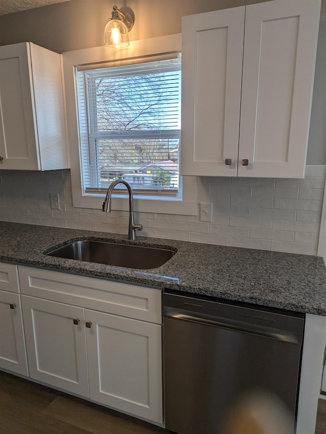 kitchen with sink, dishwasher, dark stone counters, white cabinets, and tasteful backsplash