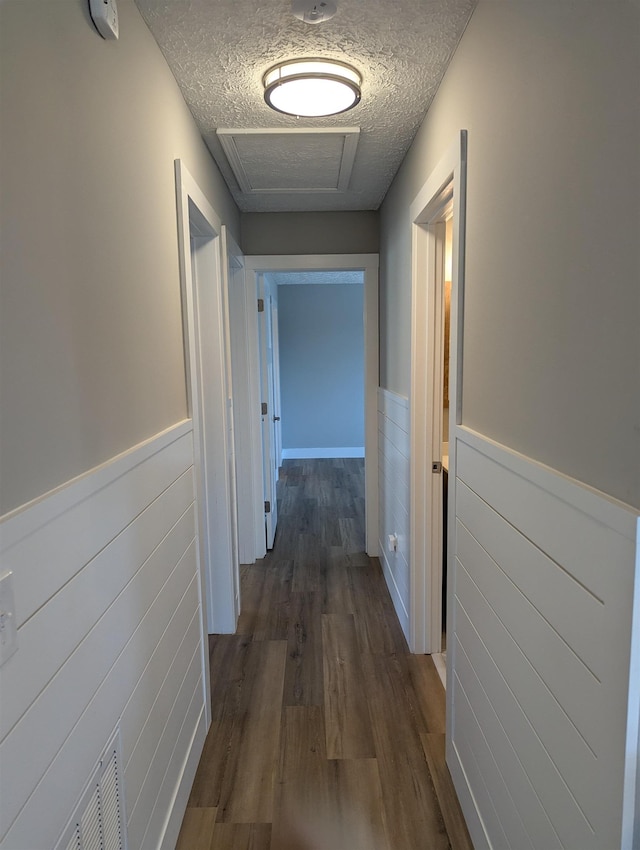 hallway with a textured ceiling and dark hardwood / wood-style floors