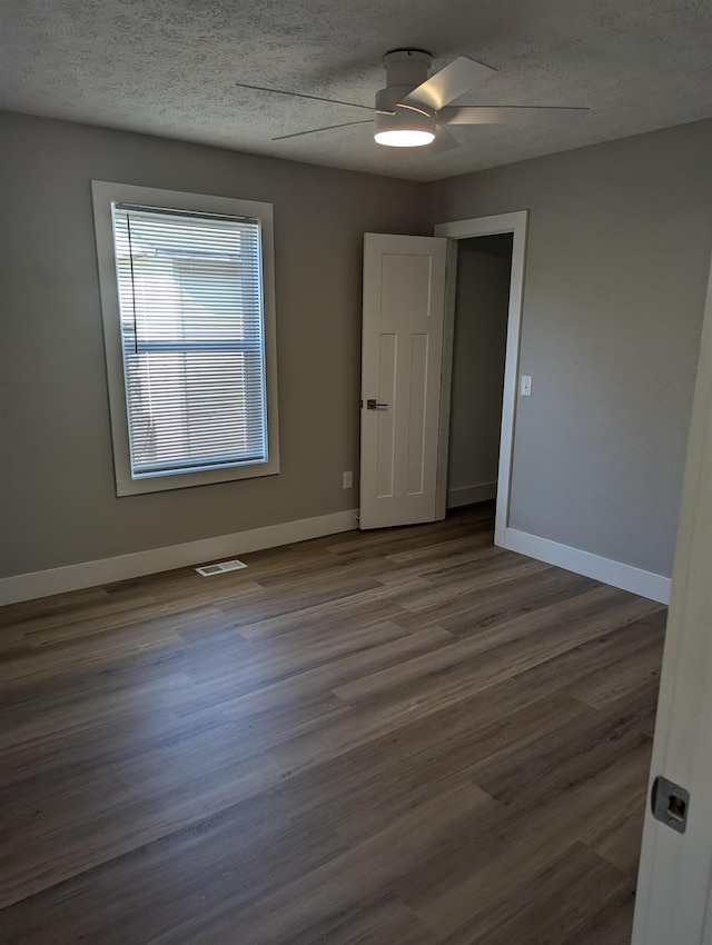 empty room featuring a textured ceiling, ceiling fan, and dark hardwood / wood-style floors