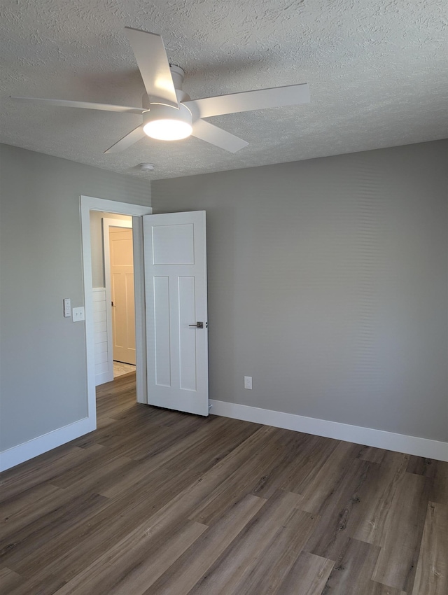 spare room featuring ceiling fan, dark wood-type flooring, and a textured ceiling