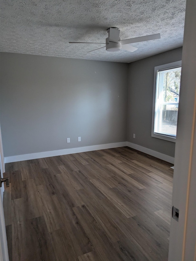 empty room featuring ceiling fan, dark wood-type flooring, and a textured ceiling