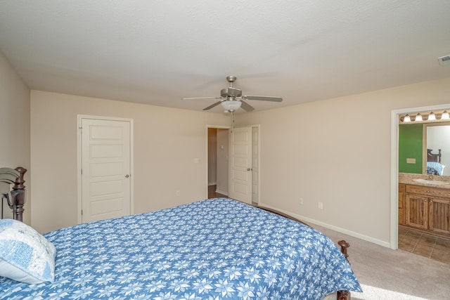 carpeted bedroom with sink, a textured ceiling, ceiling fan, and ensuite bath