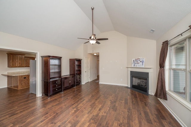 unfurnished living room featuring dark hardwood / wood-style flooring, vaulted ceiling, and ceiling fan