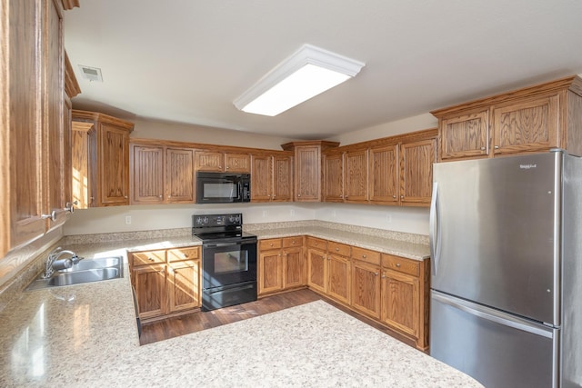 kitchen with sink, hardwood / wood-style floors, kitchen peninsula, and black appliances