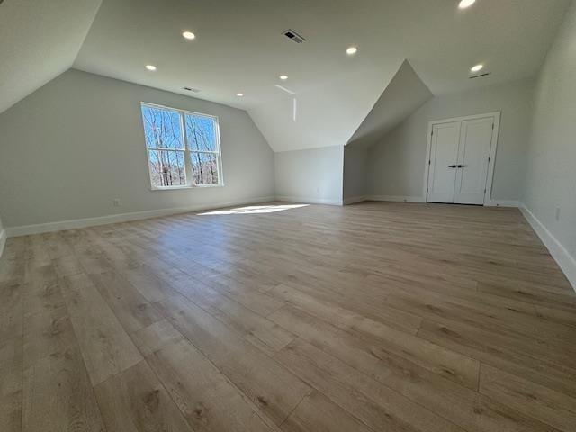 additional living space featuring vaulted ceiling and light wood-type flooring