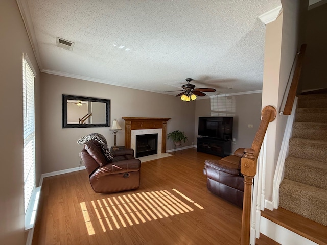 living room featuring ornamental molding, a fireplace, hardwood / wood-style floors, and a textured ceiling