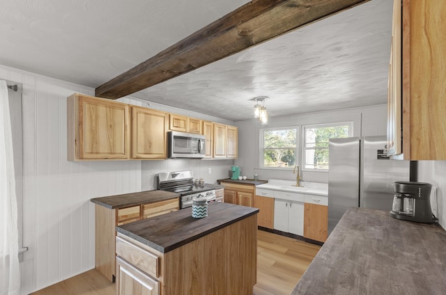 kitchen with sink, light brown cabinets, light wood-type flooring, stainless steel appliances, and beam ceiling