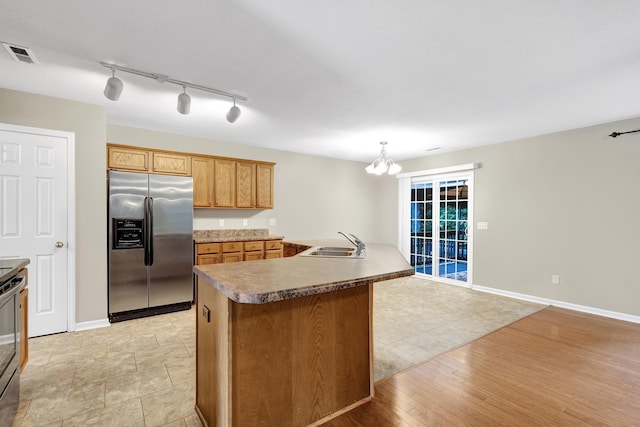 kitchen with pendant lighting, sink, a center island, stainless steel appliances, and light wood-type flooring