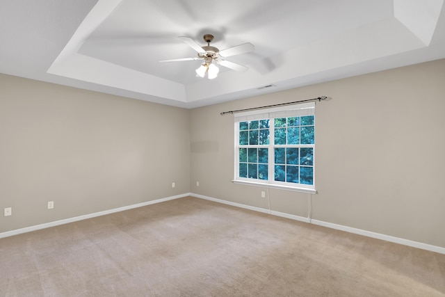 carpeted empty room featuring a raised ceiling and ceiling fan