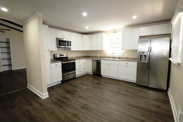 kitchen featuring appliances with stainless steel finishes, white cabinetry, sink, crown molding, and dark wood-type flooring