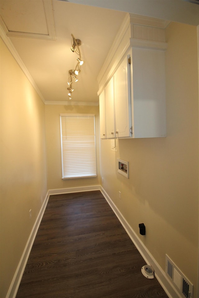 clothes washing area featuring rail lighting, cabinets, ornamental molding, washer hookup, and dark wood-type flooring