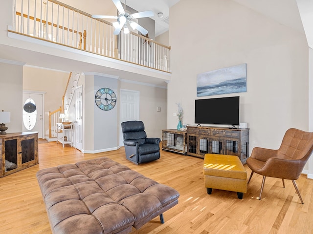 living room with a high ceiling, ornamental molding, and light wood-type flooring