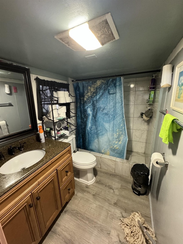 full bathroom with hardwood / wood-style flooring, vanity, shower / tub combo with curtain, and toilet