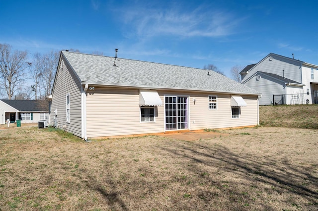 rear view of house with central AC unit and a yard