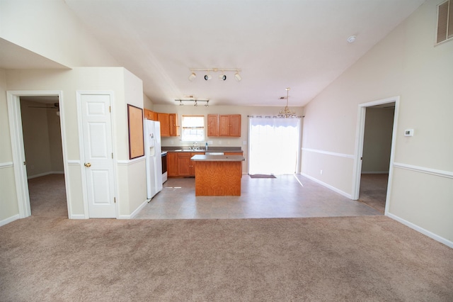 kitchen featuring light carpet, hanging light fixtures, vaulted ceiling, and a kitchen island