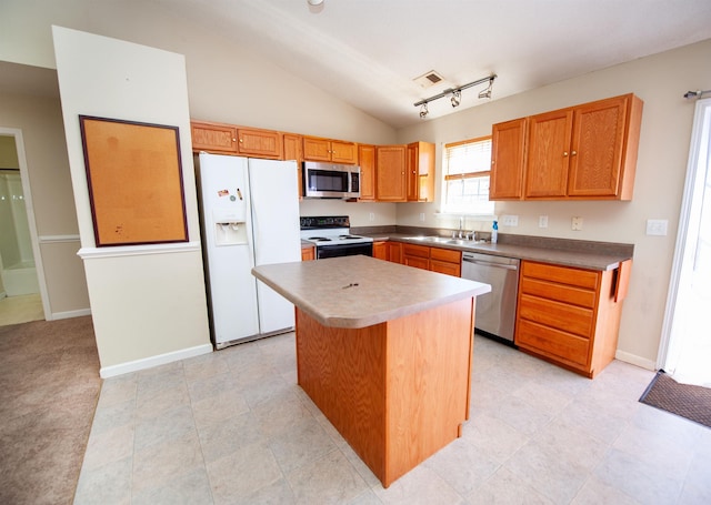 kitchen with appliances with stainless steel finishes, sink, vaulted ceiling, rail lighting, and a kitchen island