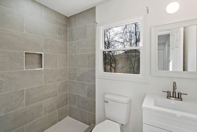 bathroom with vanity, tiled shower, and toilet