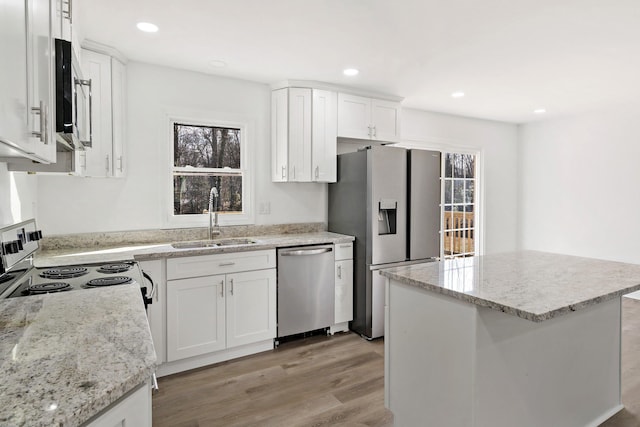 kitchen featuring sink, light stone counters, white cabinetry, a kitchen island, and stainless steel appliances