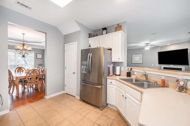 kitchen featuring decorative light fixtures, stainless steel fridge, sink, light tile patterned floors, and white cabinets