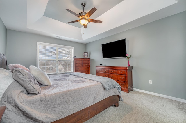 carpeted bedroom with a tray ceiling and ceiling fan