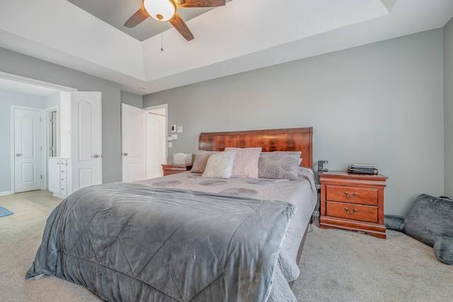 carpeted bedroom with ceiling fan and a tray ceiling