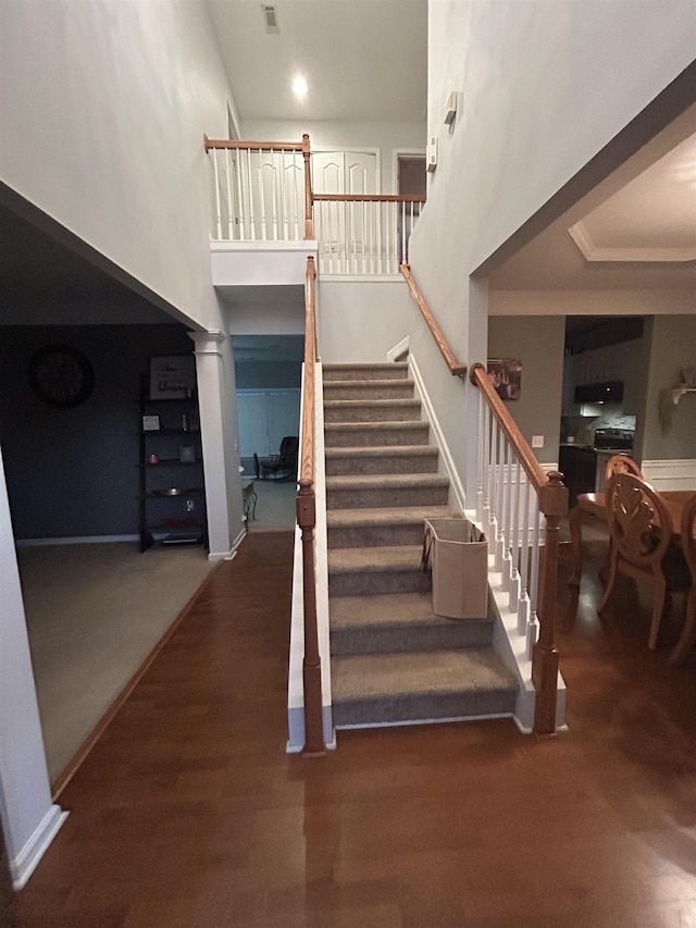 staircase featuring wood-type flooring and a towering ceiling