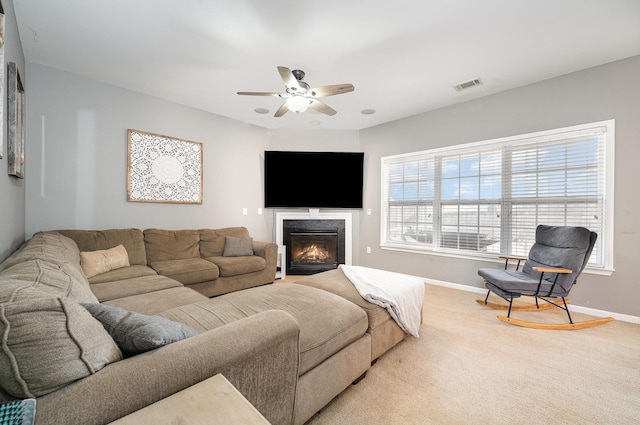 carpeted living room with a fireplace and ceiling fan