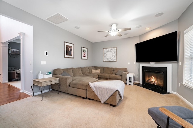 carpeted living room featuring ceiling fan and decorative columns