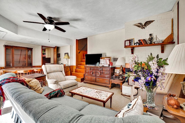 living room featuring ceiling fan, carpet flooring, and a textured ceiling