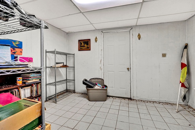 basement with a drop ceiling and wooden walls