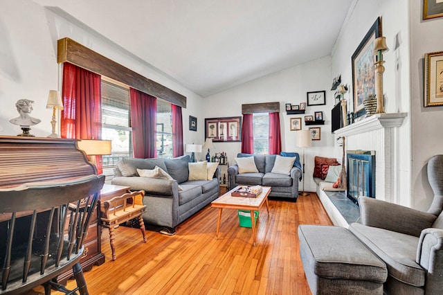 living room featuring a brick fireplace, vaulted ceiling, and hardwood / wood-style floors