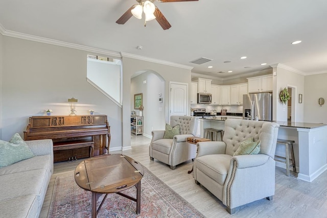 living room with light wood-type flooring, crown molding, and ceiling fan