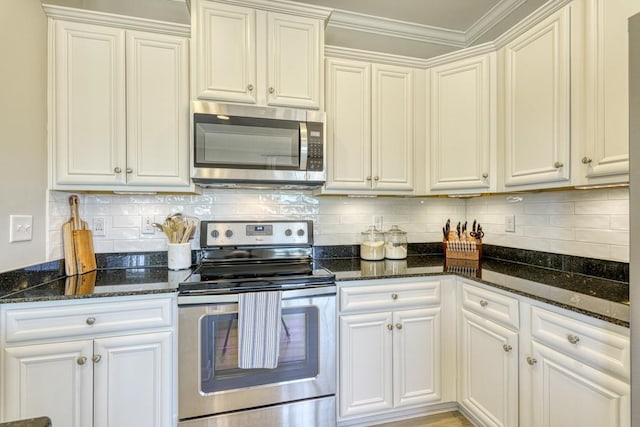 kitchen featuring stainless steel appliances, white cabinetry, dark stone counters, and backsplash