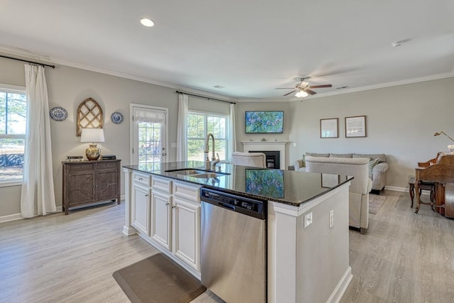 kitchen featuring an island with sink, sink, ornamental molding, stainless steel dishwasher, and white cabinets